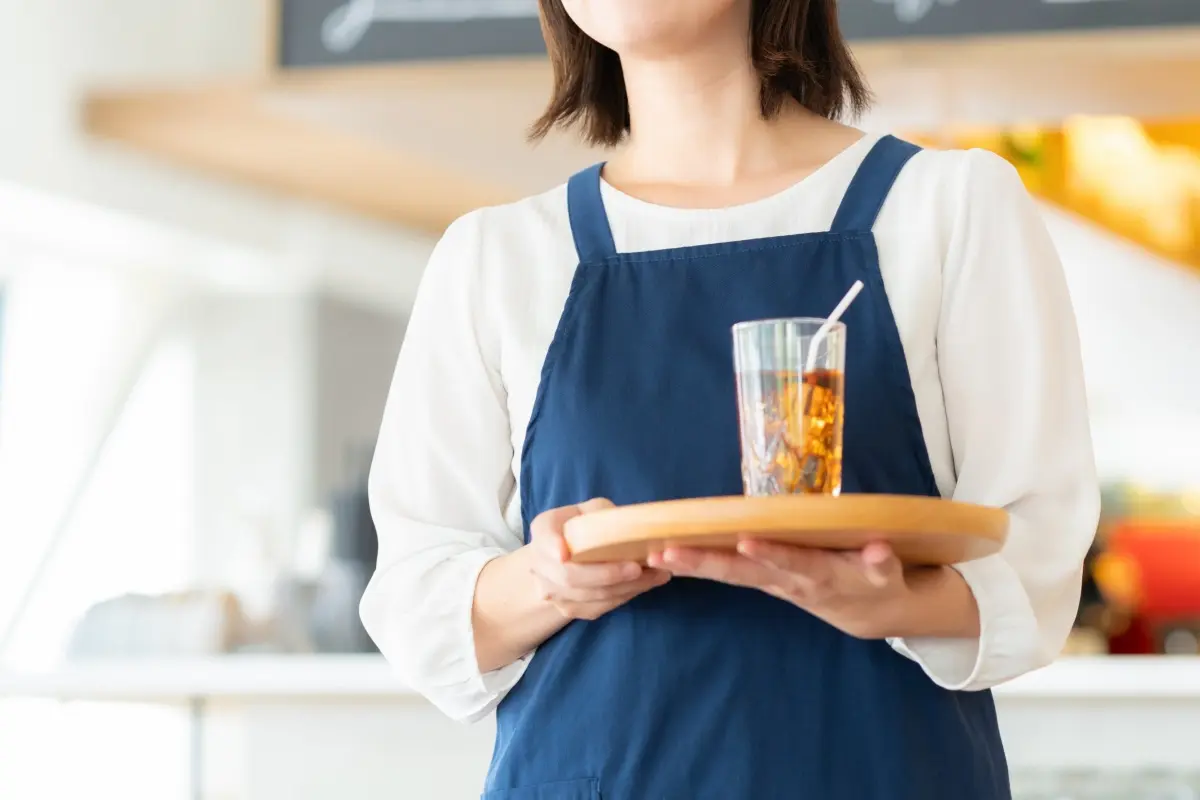 お客様に飲み物を提供する飲食店の女性